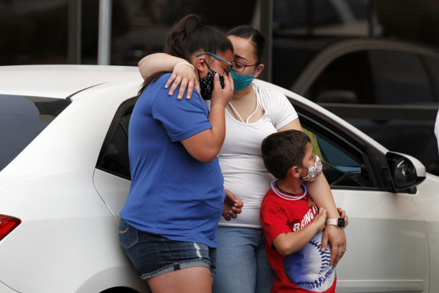 지난 5월 미국 텍사스 엘파소의 한 메디컬센터 주차장에서 열린 추모식에서 남편을 잃은 여성이 아이들을 안아주고 있다. 이 여성의 남편은 백인우월주의자가 벌인 총기난사 사건으로 목숨을 잃었다. /AP연합뉴스