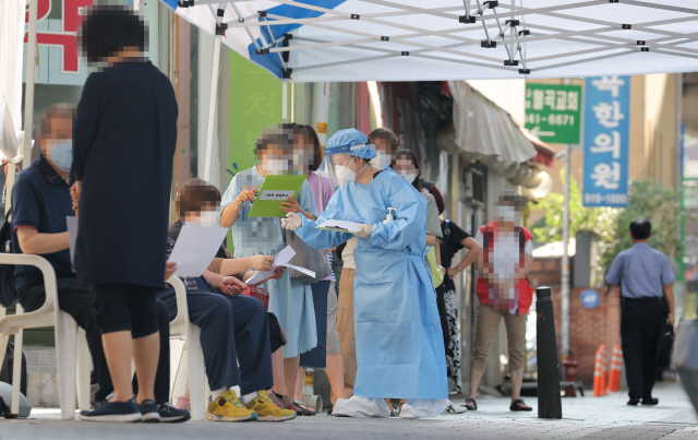 24일 오전 서울 성북구보건소에 마련된 코로나19 선별진료소에서 시민들이 검사를 받기 위해 줄을 서 있다./연합뉴스