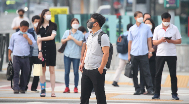 서울 지역 실·내외 마스크 의무착용 행정명령 발동 이틀째인 25일 오전 서울 세종로사거리에서 마스크를 쓴 시민들이 출근하고 있다. /연합뉴스