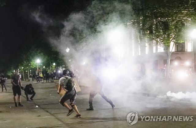 미국 위스콘신주 커노샤에서 24일(현지시간) ‘흑인 피격’에 항의하는 시위대가 경찰이 쏜 최루탄을 피해 달아나고 있다. /EPA연합뉴스