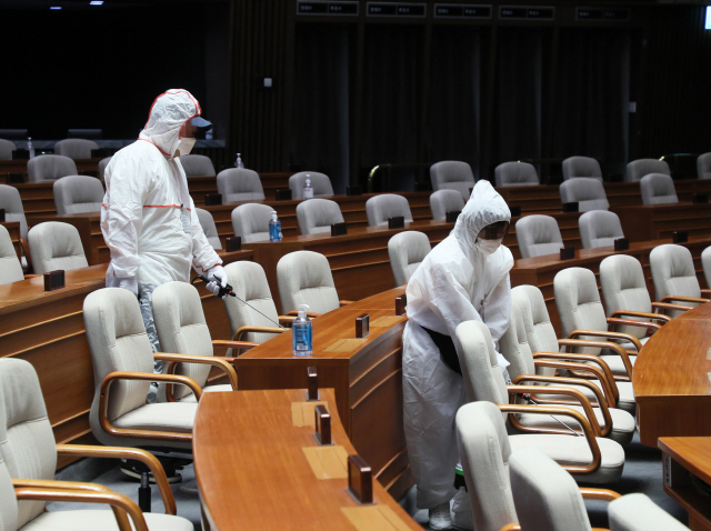 신종 코로나바이러스 감염증(코로나19) 확진자 발생으로 국회가 폐쇄된 26일 자정께 방역 관계자들이 국회의사당 본회장에서 방역 작업을 하고 있다.  /연합뉴스