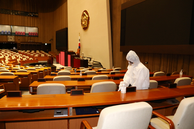 신종 코로나바이러스 감염증(코로나19) 확진자 발생으로 국회가 폐쇄된 가운데 지난 27일 방역 관계자들이 국회의사당 본회장에서 방역 작업을 하고 있다. /연합뉴스