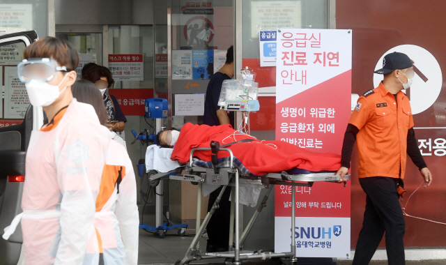 서울대병원 내과 교수진이 외래진료 축소를 선언한 28일 진료 지연 안내문이 설치된 응급실로 환자가 이송되고 있다.  /권욱기자