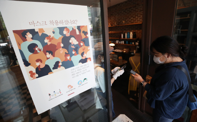 지난  24일 서울의 한 카페에서 직원이 전자출입명부 기록을 위해 출입 손님들의 QR코드를 인식하고 있다./연합뉴스