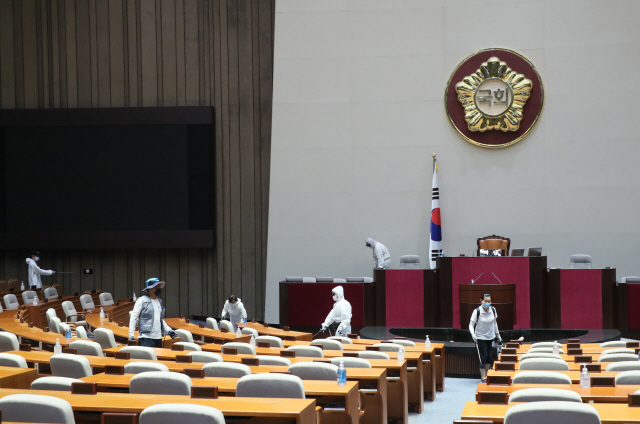 신종 코로나바이러스 감염증(코로나19) 확진자 발생으로 국회가 폐쇄된 26일 밤 방역 관계자들이 국회의사당 본회장에서 방역 작업을 하고 있다. /연합뉴스