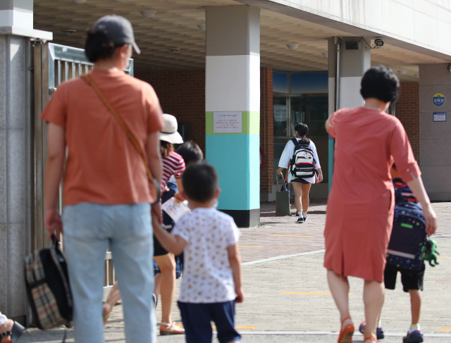 지난 25일 오전 서울 마포구의 한 초등학교에서 등교하는 학생들을 바라보는 학부모 모습. /연합뉴스