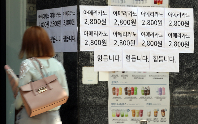 최근 수도권의 신종 코로나바이러스 감염증(코로나19) 확산으로 인한 강화된 2단계 사회적 거리 두기로 자영업자들의 시름이 깊어지는 가운데 1일 서울의 한 커피전문점에 ‘힘듭니다’라고 적혀있는 문구 앞으로 행인이 지나가고 있다. /연합뉴스