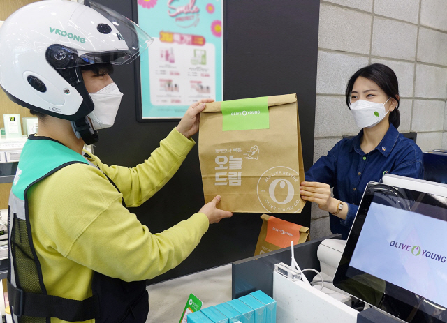 CJ올리브영 매장에서 직원이 고객에게 배송할 오늘 드림 상품을 배달기사에게 건네주고 있다. /사진제공=CJ올리브영