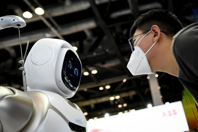 교역회에 참석한 한 관람자가 서비스 로봇을 주의 깊에 살펴보고 있다. /AFP연합뉴스