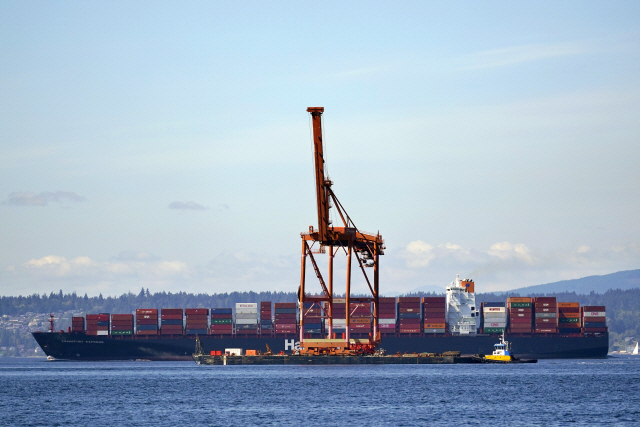 크레인을 실은 바지선이 지난 8월26일 미국 시애틀 인근 퓨젓 사운드 만에서 컨테이너를 가득 적재한 배 앞을 지나가고 있다. /AP연합뉴스