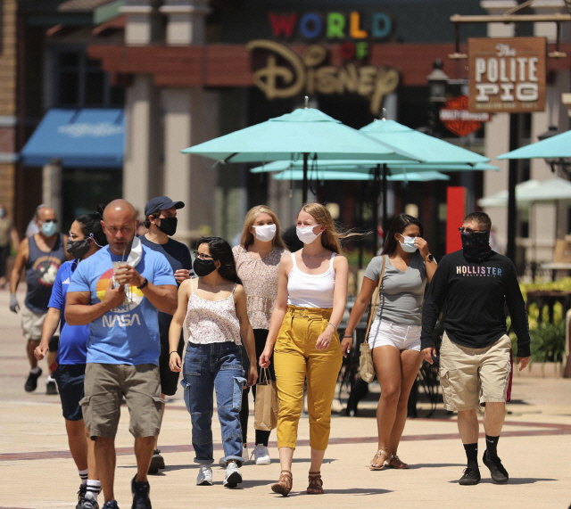 미국 올랜도에 위치한 디즈니 스프링스 앞을 마스크를 쓴 관광객들이 지나가고 있다. /AP연합뉴스