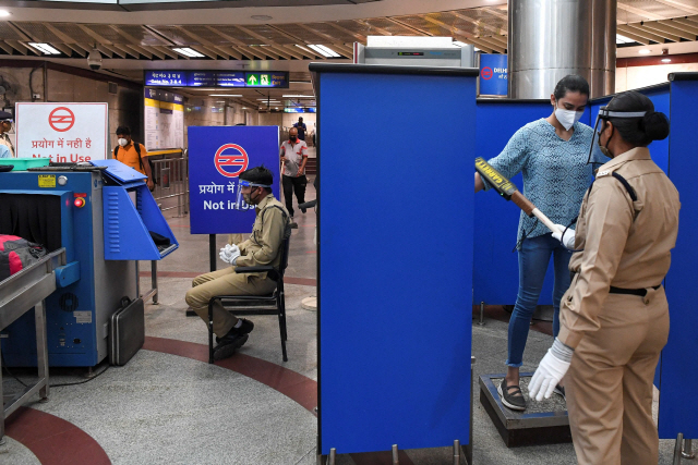 인도 수도 뉴델리에서 코로나19 대유행으로 중단됐던 지하철 운행이 재개된 7일(현지시간) 한 보안요원이 탑승객을 대상으로 검문·검색을 진행하고 있다./AFP연합뉴스