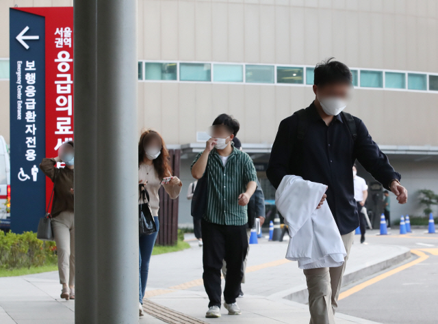 전공의들이 집단휴진을 벌인 지 18일 만에 업무에 복귀한 8일 오전 서울대병원에서 한 전공의가 가운을 들고 본관으로 이동하고 있다. /연합뉴스