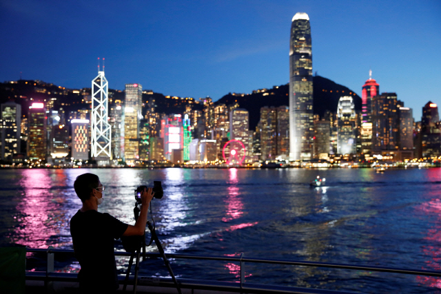 홍콩 카오룽의 침사추이 지역에서 한 남성이 홍콩섬의 야경을 촬영하고 있다. /로이터연합뉴스