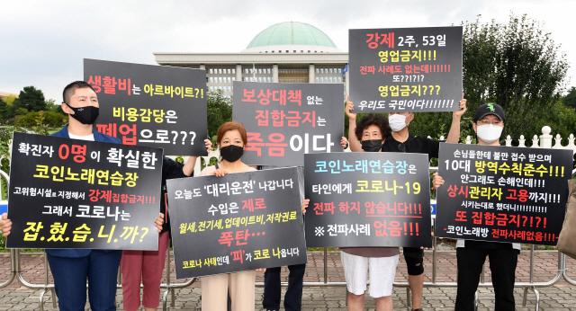 코인노래방 업주들이 9일 서울 여의도 국회 앞에서 생존권을 위한 기자회견을 열고 피해 규모에 맞는 보상을 요구하는 팻말을 들어보이고 있다../권욱기자