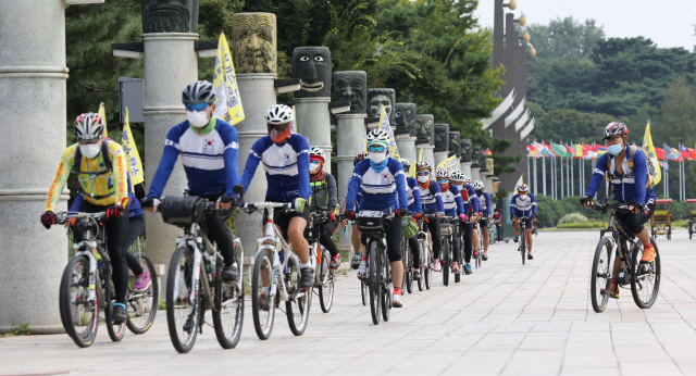 녹색자전거봉사단연합 회원들이 11일 서울 송파구 올림픽공원 세계평화의문 앞에서 열린 자전거마일리지시민가입 시민자전거홍보단 발대식에서 온실가스 줄이기 홍보를 위한 퍼포먼스를 벌이고 있다./연합뉴스