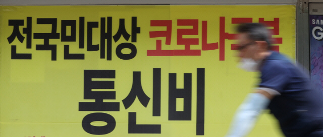 서울 시내 한 통신사 매장에 걸린 통신비 인하 관련 현수막 앞을 한 시민이 지나가고 있다/연합뉴스