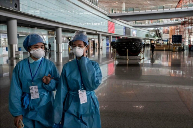 지난 3월16일 입·출국자가 줄어 텅비어 버린 중국 베이징 서우두공항에서 방역인력들이 터미널을 지나가고 있다. /AFP연합뉴스