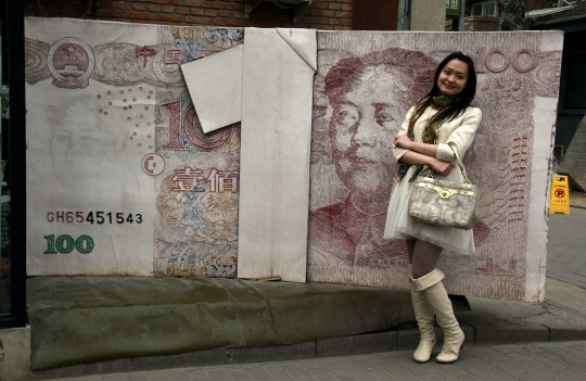 중국 베이징에 설치된 대형 모형 위안화 조각상 앞에서 한 시민이 기념사진을 찍고 있다. /연합뉴스
