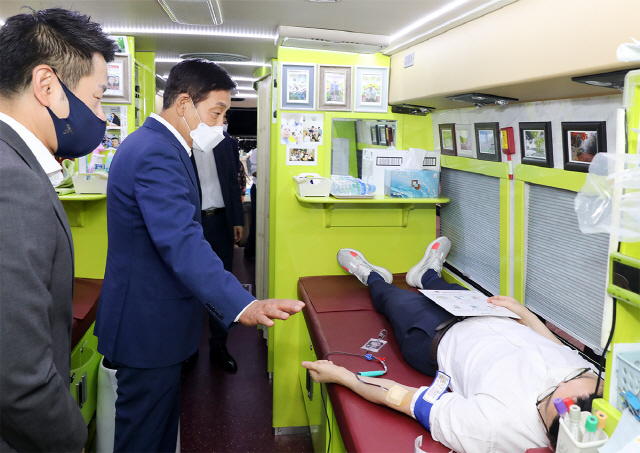 김정태(가운데) 하나금융그룹 회장이 17일 하나금융그룹 명동사옥 야외주차장에 마련된 헌혈버스를 찾아 헌혈 캠페인에 참여한 직원을 격려하고 있다./사진제공=하나금융