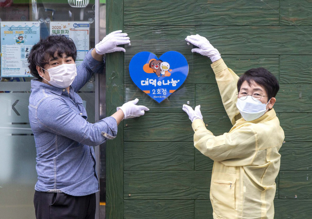 박정현(사진 오른쪽) 대덕구청장이 ‘대덕e나눔’ 2호점에 지정현판을 걸어주고 있다. 사진제공=대덕구