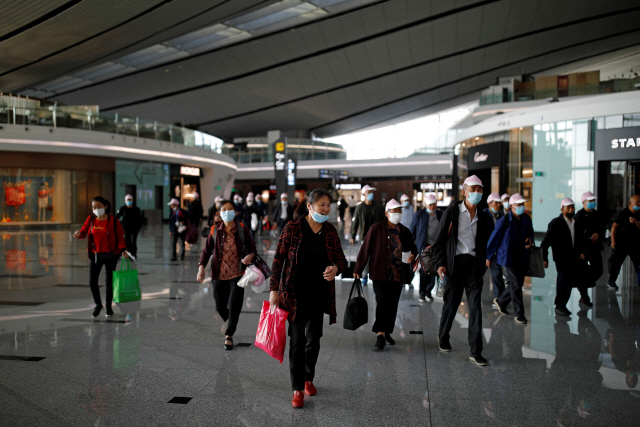 20일 중국 베이징의 다싱 공항에서 마스크를 쓴 여행객들이 걸어가고 있다. /로이터연합뉴스
