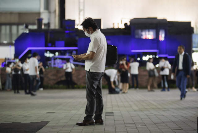 만남의 장소로 유명한 일본 도쿄의 한 기차역 주변에서 18일 마스크를 쓴 한 남성이 스마트폰을 보고 있다. /AP연합뉴스