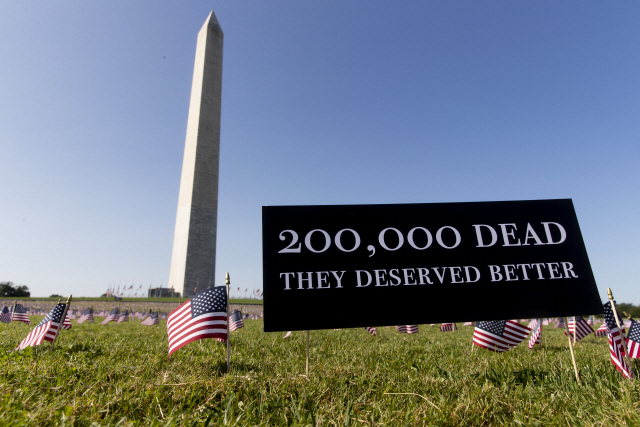 22일(현지시간) 미국 워싱턴DC 워싱턴기념탑 앞 잔디밭에 코로나19로 사망한 미국인들을 추모하는 수천개의 작은 성조기들과 ‘사망자 20만명, 그들은 더 나은 대접을 받을 자격이 있었다’라고 적힌 표지판이 꽂혀 있다.이날 존스홉킨스대 기준으로 미국의 코로나19 사망자는 20만명을 넘었다. /EPA연합뉴스