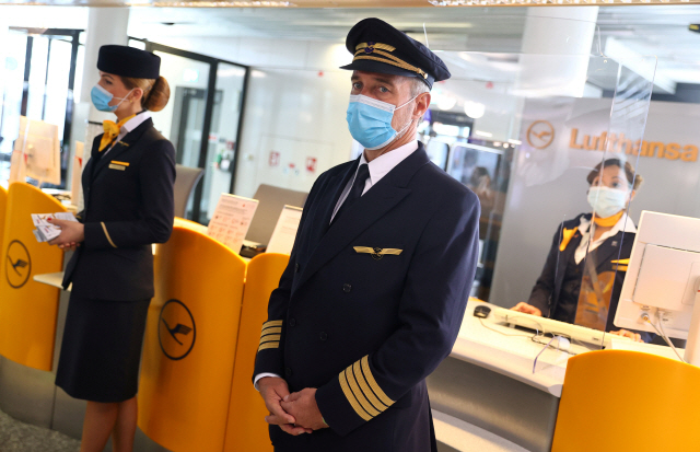 루프트한자 직원들이 지난 17일 독일 프랑크푸르트 공항에서 마스크를 쓴 채 탑승객들을 기다리는 모습. /로이터연합뉴스