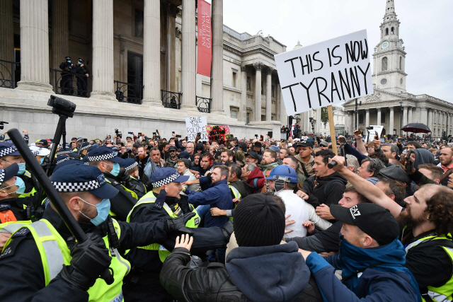26일(현지시간) 영국 런던 도심의 트래펄가광장에서 술집 영업시간 제한과 6인 이상 모임 금지 등 코로나19 방역을 위한 사회적 거리두기 지침에 항의하는 시민들이 경찰과 몸싸움을 벌이고 있다./AFP연합뉴스