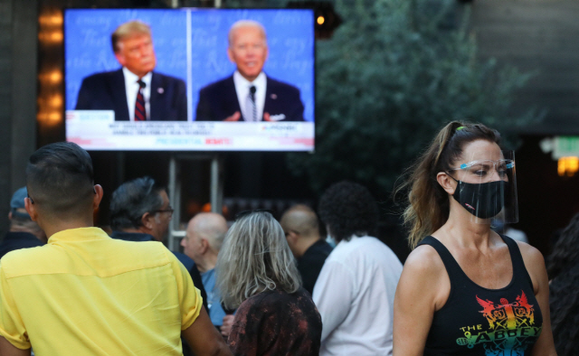 29일(현지시간) 미국 캘리포니아주에서 마스크를 쓴 사람들이 야외에 설치된 TV를 통해 미 대선 후보 간 첫 토론회를 보고 있다./AFP연합뉴스