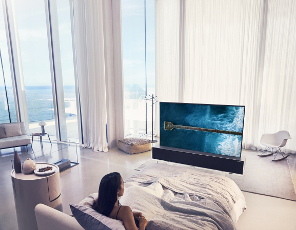 LG전자 모델이 침실에서 롤러블 TV ‘LG 시그니처 올레드 R’을 시청하고 있다. /사진제공=LG전자