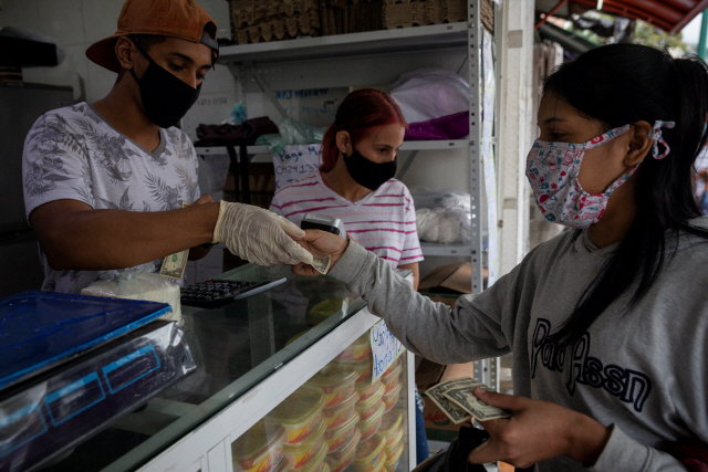 지난 7월 베네수엘라 카라카스의 한 상점에서 여성이 미 달러화로 결제하고 있다. /EPA