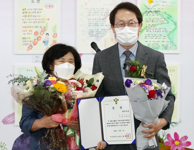 7일 오후 서울 서대문구 서울시교육청에서 열린 ‘2020 서울시교육청 학력인정 문해교육 10주년 기념시화전’에서 작품 ‘나도 이제 알아’로 최우수상을 받은 추정순(왼쪽)씨가 조희연 서울시교육감과 기념촬영을 하고 있다. 문해교육은 문자를 읽고 쓰도록 도와주는 교육 프로그램으로 이수하면 초·중학교 졸업 학력을 인정받을 수 있다. /연합뉴스