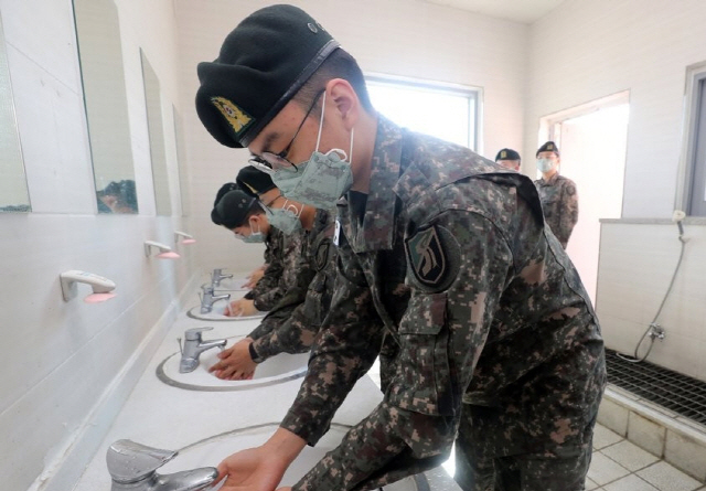 군 장병들이 신종 코로나바이러스 감염증 예방을 위해 마스크를 착용하고 손을 씻고 있다.     /연합뉴스