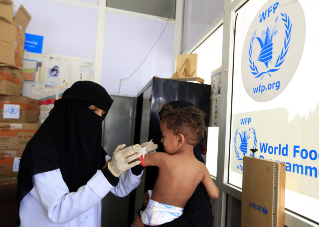 지난해 6월 예멘 수도 사나에서 세계식량계획(WFP)의 한 직원이 어린이를 치료해주고 있다. /AFP연합뉴스