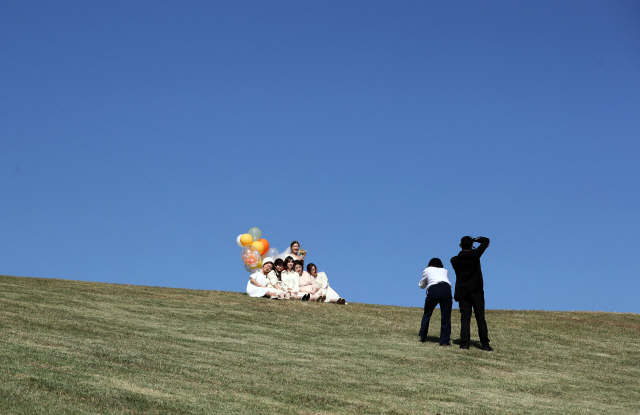 9일 서울 송파구 올림픽 공원에서 결혼을 앞둔 예비신부와 친구들이 파란 하늘을 배경으로 사진 촬영을 하고 있다. /연합뉴스