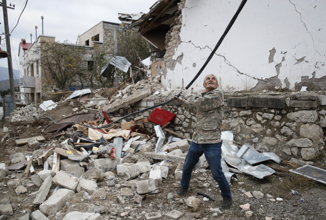 아제르바이잔과 아르메니아가 휴전에 합의한 후인 10일(현지시간) 나고르노카라바흐 지역 스테파나레스트의 파괴된 건물 앞에서 한 남성이 전력선을 수리하고 있다. /AP연합뉴스