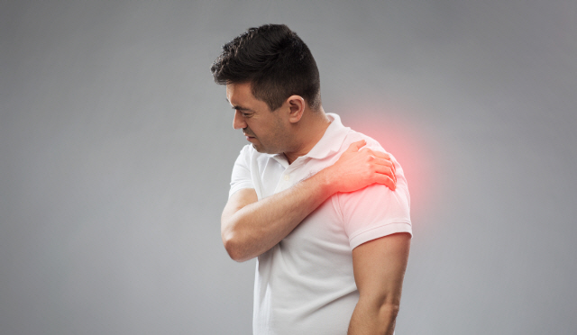 people, healthcare and problem concept - unhappy man suffering from pain in shoulder over gray background