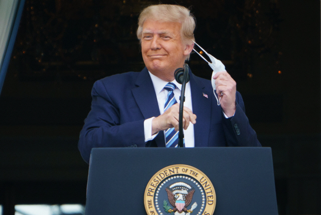 지난 10일(현지시간) 도널드 트럼프 미국 대통령이 백악관에서 연설하기 위해 마스크를 벗고 있다./AFP연합뉴스I