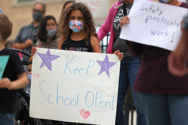 앤드루 쿠오모 미국 뉴욕주지사가 코로나19 재확산 위험이 큰 일부 지역 내 학교를 폐쇄하자 지난 7일(현지시간) 한 아이가 ‘학교를 개방하라(Keep school open)’라고 적힌 팻말을 들고 시위를 벌이고 있다./AFP연합뉴스