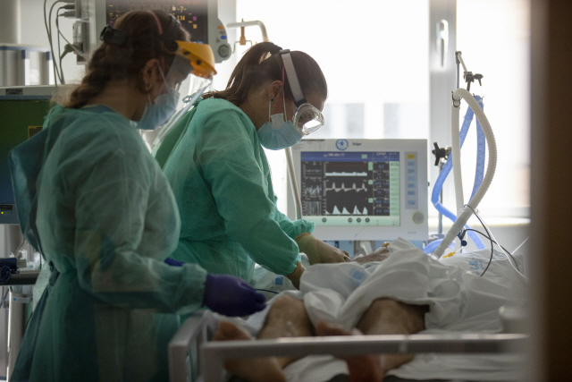 지난 6일(현지시간) 스페인 토레혼데아르도스의 한 병원에서 의료진들이 코로나19 확진 판정을 받은 환자를 진찰하고 있다./AP연합뉴스