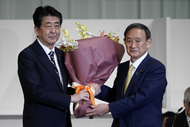 아베 신조(왼쪽) 일본 총리가 지난 9월14일 신임 자민당 총재로 선출된 스가 요시히데 관방장관에게 당선 축하 꽃다발을 전달하고 있다. /도쿄=AP연합뉴스