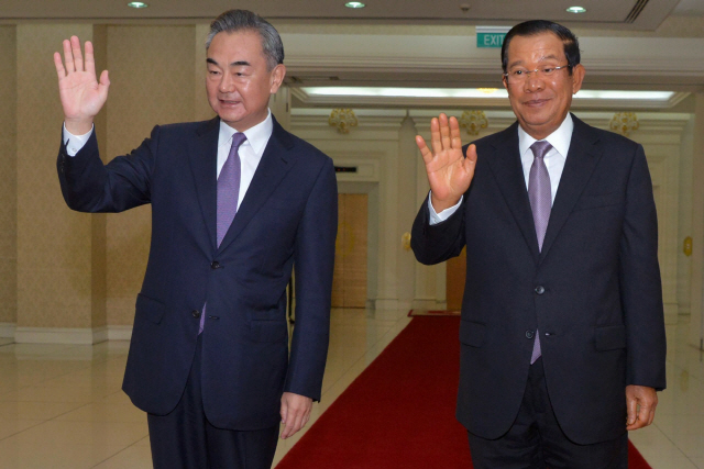 12일(현지시간) 캄보디아를 찾은 왕이(왼쪽) 중국 외교담당 국무위원 겸 외교부장과 훈센 캄보디아 총리가 프놈펜 평화궁전에서 카메라를 향해 손을 들어보이고 있다. 왕 부장은 지난 11일부터 오는 15일까지 캄보디아와 말레이시아·라오스·태국·싱가포르 등 동남아 5개국을 순방한다./AFP연합뉴스