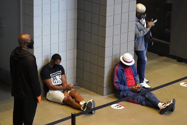 12일(현지시간) 미국 조지아주 애틀랜타에서 사전투표를 하기 위해 기다리고 있는 유권자들이 긴 기다림에 지쳐 앉아있다./AP연합뉴스