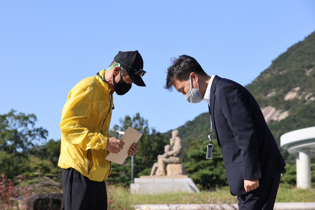 북한 피격 사망 공무원 A씨의 형 이래진 씨(왼쪽)가 8일 오후 서울 종로구 청와대 분수광장에서 A씨의 아들이 문재인 대통령에게 보내는 자필 편지 원본을 시민사회수석실 행정관에게 전달하고 있다. /연합뉴스