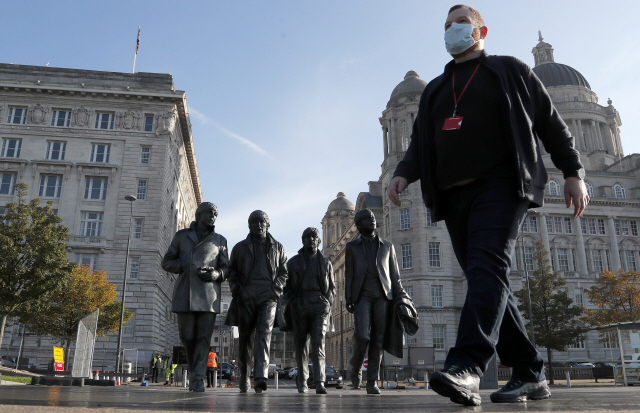 마스크를 쓴 영국 리버풀의 한 남성이 14일(현지시간) 비틀즈 동상 앞을 걷고 있다. AP연합뉴스