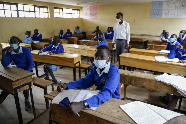 코로나19로 폐쇄됐던 학교가 다시 개방한 날인 12일(현지시간) 케냐 수도 나이로비의 한 초등학교에 마스크를 쓴 아이들이 등교해 책상 앞에 앉아있다./AP연합뉴스