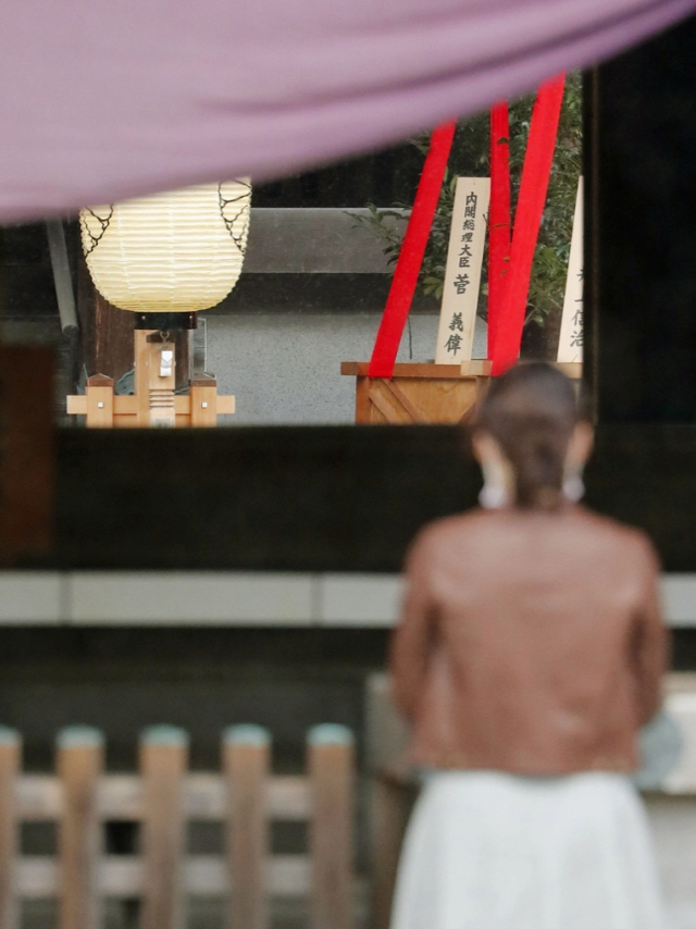 스가 요시히데 일본 총리가 17일 야스쿠니 신사의 가을 큰 제대에 맞춰 ‘마사카키’(木+神)로 불리는 공물을 봉납했다. 이날 한 참배객이 야스쿠니 제단에 놓인 스가 총리 명의의 ‘마사카키’ 앞에서 예를 올리고 있다./연합뉴스