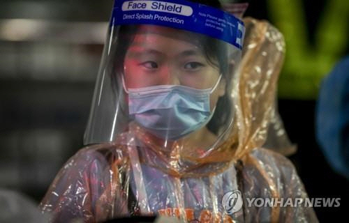 얼굴 가리개를 쓰고 비옷을 입은 중국인 관광객이 방콕 수완나폼 공항을 나서고 있다./AP연합뉴스
